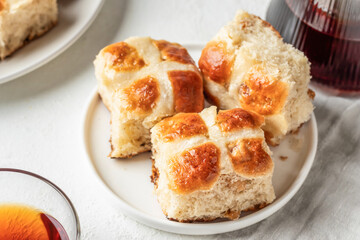 Traditional Easter hot cross buns on white plate on white background with tea. Delicious Easter breakfast