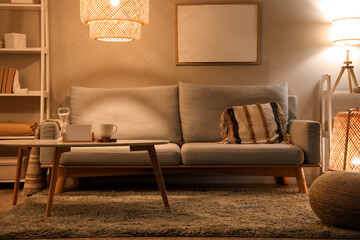 Interior of modern living room with grey sofa, coffee table and glowing lamps at evening