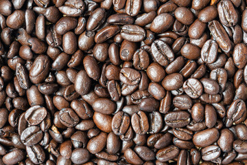 Low quality coffee beans. Close-up of medium roasted coffee beans. Arabica coffee background.