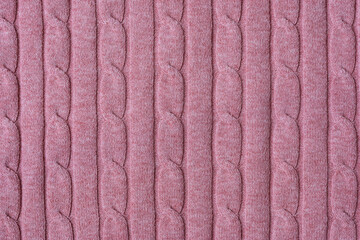 Texture of hand-knitted fabric made of pink threads, cables knitting stitch pattern