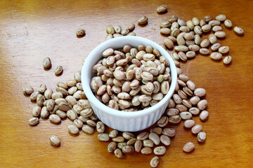 Pinto grains in a bowl on the wooden table. Brazilian beans.