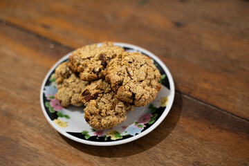 cookies, oatmeal cookies resting over a little dish plate, on a wooden table