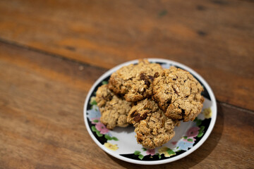 cookies, oatmeal cookies resting over a little dish plate, on a wooden table