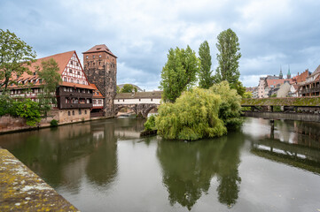 Obraz premium Nuremberg, Germany, August 1, 2023. Photo with an iconic image of the fairytale atmosphere of the place. The half-timbered house is reflected in the water, rainy day. Travel destinations.