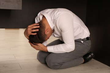 Scared man hiding under office desk during earthquake
