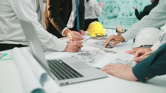 A diverse team engaged in a collaborative engineering project, focusing on detailed drawings and tools while ensuring safety with helmets in a modern workspace. SACTR