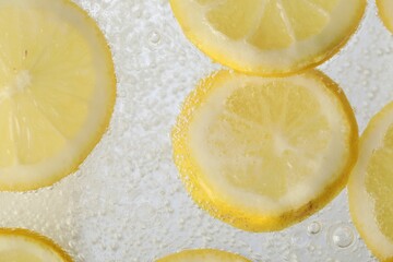 Soda water with lemon slices as background, closeup