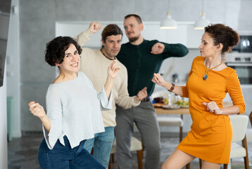 Friends dancing. Cheerful young people dancing and drinking while enjoying home party on the room