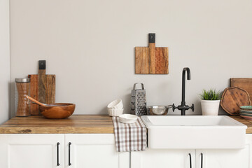 Ceramic sink on wooden counter and utensils in kitchen. Closeup