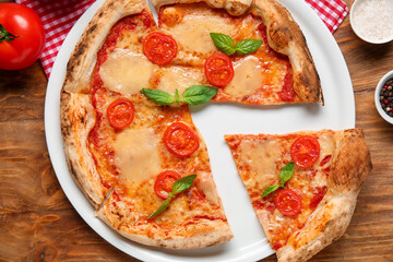 Plate with cut tasty pizza Margarita on wooden background
