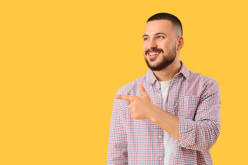 Young man pointing at something on yellow background. Rules concept