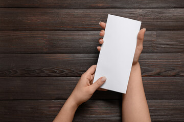 Obraz premium Female hands with blank brochure on wooden background