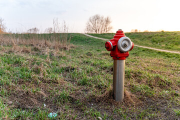 Hydrant na tle zielonego krajobrazu – Czerwony akcent pośród naturalnego otoczenia.