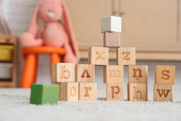 Cubes with letters on floor in children's playroom, closeup