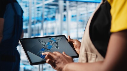 Industry 4.0 industrial plant engineer designs new robotic machines using CAD software on tablet....