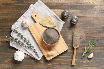 Bowl with black pepper powder and different spices on wooden background
