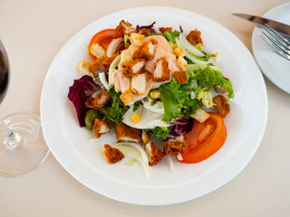 Appetizing Caesar salad with tomatoes, corn, olives and fried chicken
