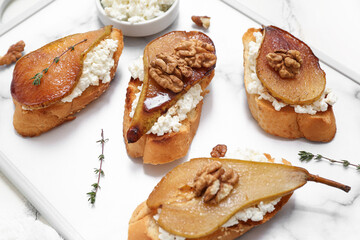 Tray of pear bruschetta with ricotta cheese, walnuts and thyme on white background