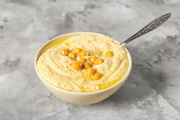 Bowl of delicious hummus with sesame seeds and chickpeas on grey grunge background