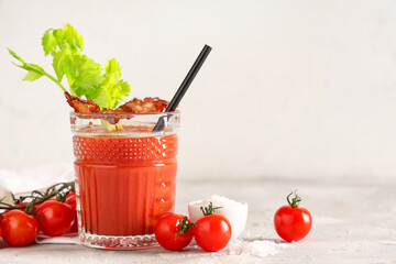 Glass of bloody mary cocktail with bacon and celery on grey table