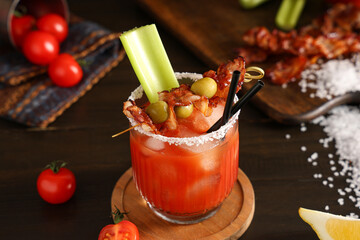 Glass of bloody mary cocktail with bacon, olives and celery on wooden background, closeup