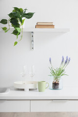 Beautiful Muscari flowers with glasses on counter in light kitchen