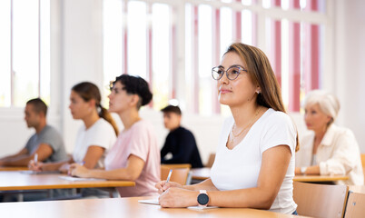 Latin young woman focused on lecture in university. Woman sitting at desk and listening carefully.