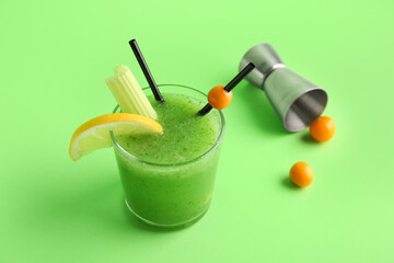 Glass of green bloody mary cocktail garnished with lemon and physalis berry on color background