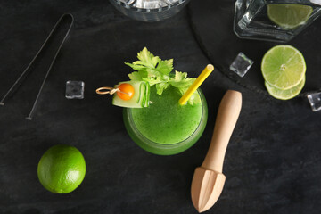 Glass of green bloody mary cocktail garnished with physalis berry and cucumber slice on black...