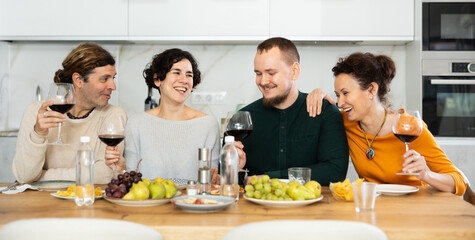 Group of happy celebrating holiday drinking and chatting at table at home