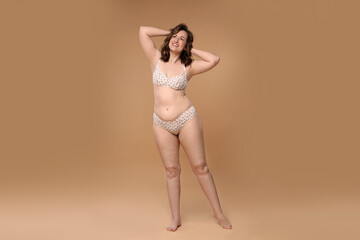 Fototapeta premium Beautiful woman in underwear on dark beige background. Cellulite problem