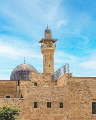 Fototapeta premium A mosque with a tall minaret and a large dome located in a sunny middle-eastern city.