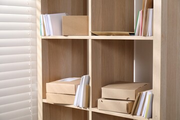 Different paper envelopes and parcels on wooden shelves in post office