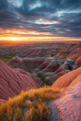 Fototapete Sunset silhouette of rugged rock formations with grassy tops, red and yellow hues in sky above. © Alexander Chaykin