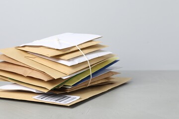 Post office. Stack of different paper envelopes on grey table, closeup. Space for text