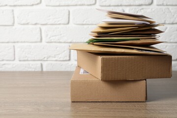 Different paper envelopes and parcels on wooden table, space for text. Post office