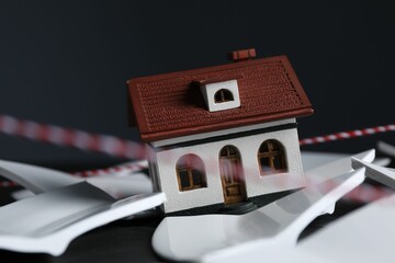 House model and broken dishes on black table depicting destruction after earthquake