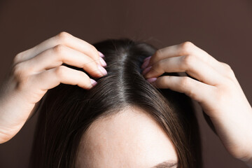 Woman with healthy hair roots on brown background, closeup