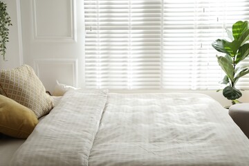 Comfortable bed with soft linens in stylish room, closeup. Interior design