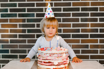 Little boy with birthday hat blowing candles