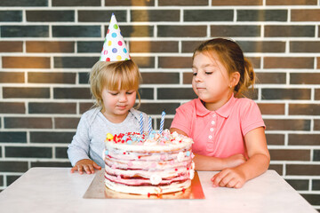 Children blowing candles on birthday cake together