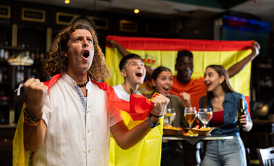 Joyful fans of the Spain team celebrating the victory in the night bar