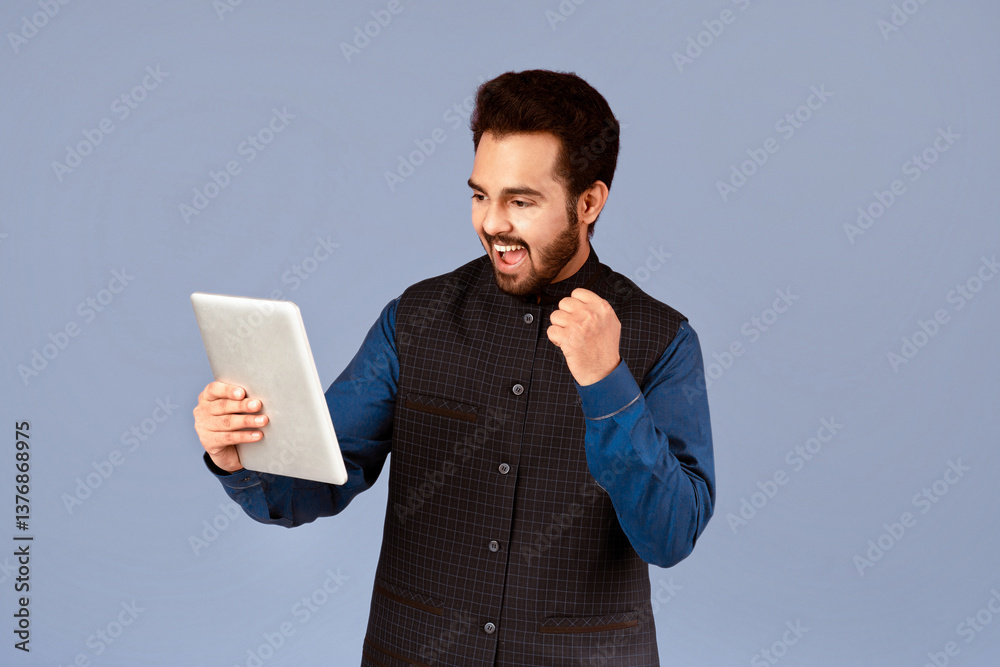 Poster Excited Indian man with tablet computer making YES gesture on violet background