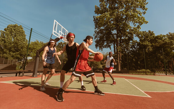 Diverse sports team playing basketball at outdoor arena on summer day, copy space. Panorama