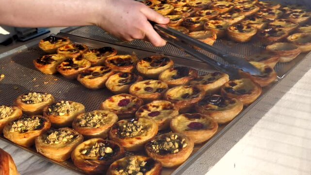 The world-famous Portuguese dessert Pastel de Nata is on display in a bakery window. The morning pastries, filled with raspberry, chocolate, grated pistachio and coconut, are sold in the sunshine(pm3)