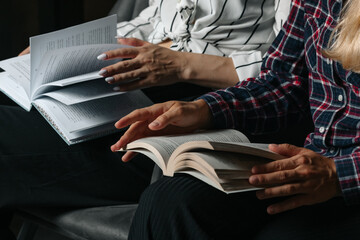 Two young women sitting in a modern office, working together on a laptop. One points at the screen while holding a credit card. Concept of teamwork, online shopping, and business collaboration.