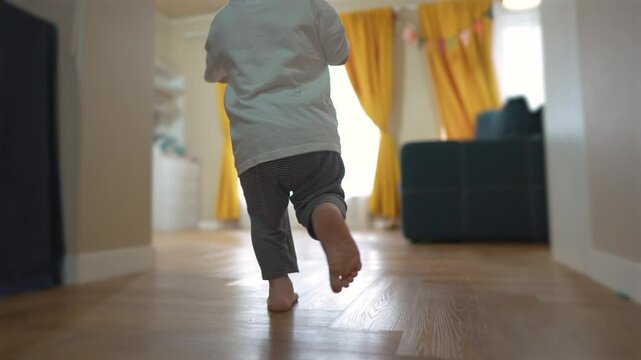 Young child walking down hallway. Baby child runs ball in a room. Happy family running a home. A little kid strolling along a corridor lifestyle.