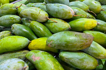 A pile of unripe, green mangoes at a market.