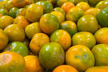 Fresh mandarin oranges, likely tangerines or satsumas, piled high for sale.