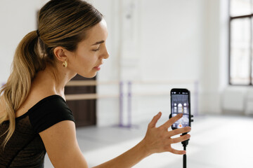 Dancer tapping screen of smartphone to adjust it for creating video